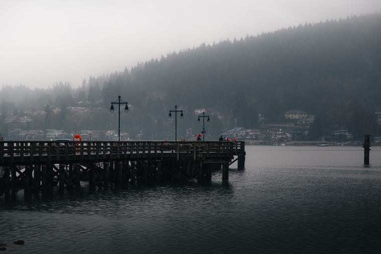 A misty pier along Port Moody's inlet with the forested hillside behind it
