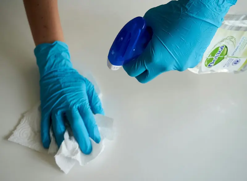 A cleaner wiping down a surface with a spray bottle